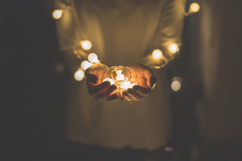 Person holding Christmas lights. The lighting is dramatic.